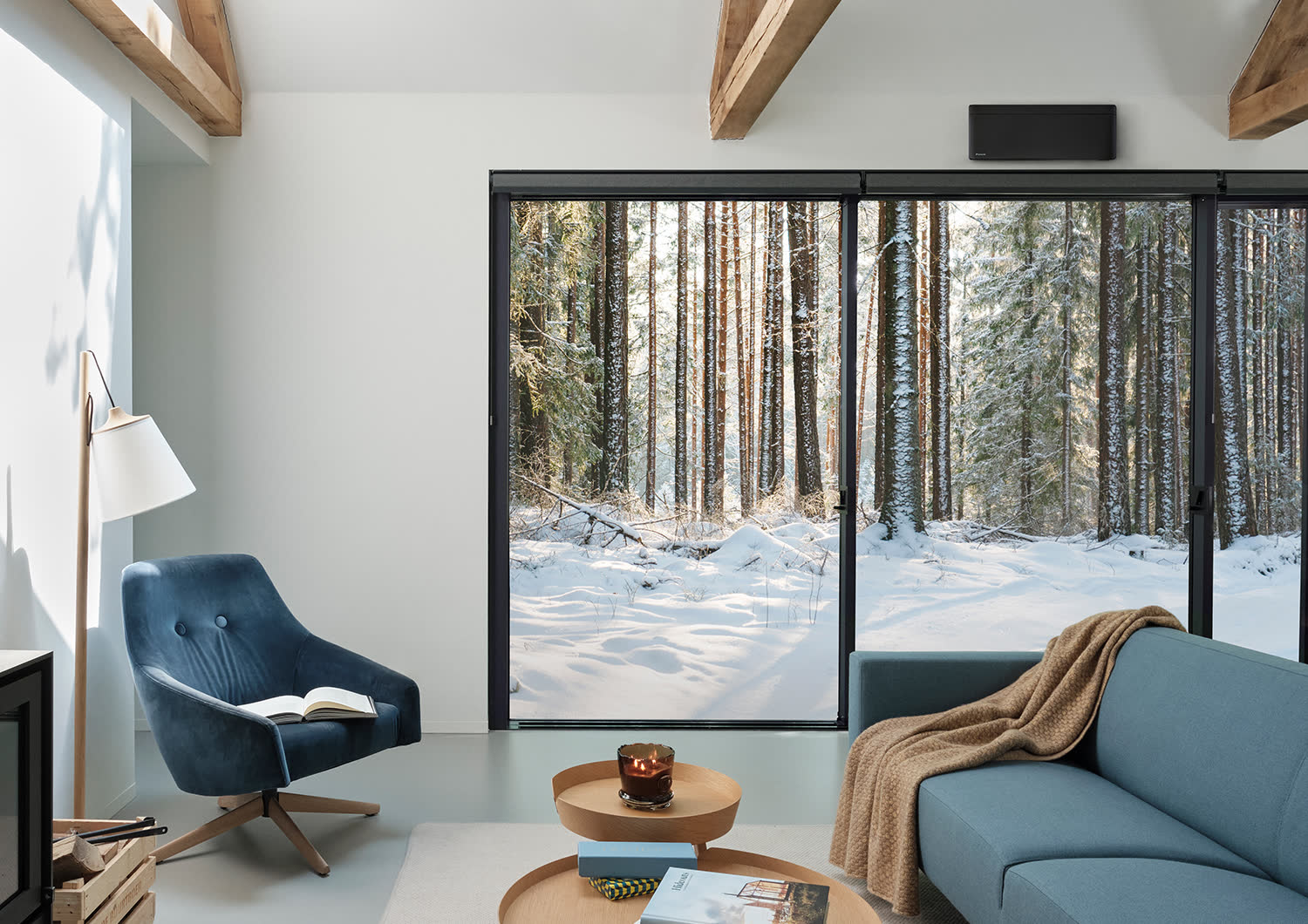 Stue med store vinduer mot snødekt skog og en innedel over vinduet